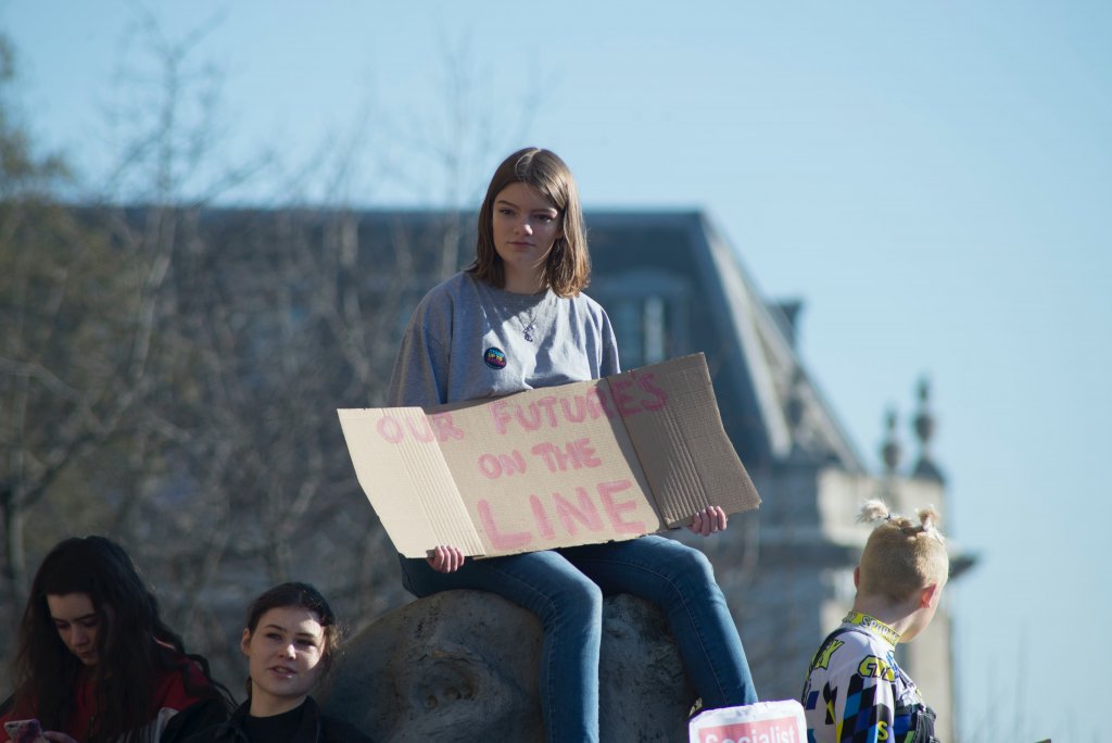 A young girl with a sign that reads "OUR FUTURES ARE ON THE LINE"